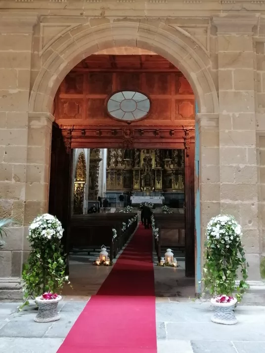 Entrada a una iglesia con plantas y flores a cada lado