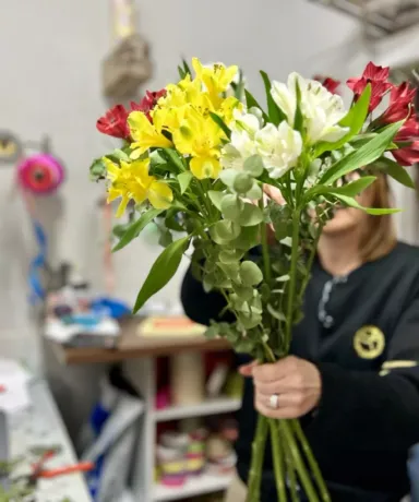 Florista sujetando un ramo de flores rojas, amarillas y blancas