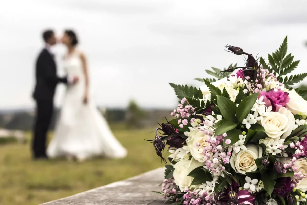 Ramo de flores de novia con los novios al fondo